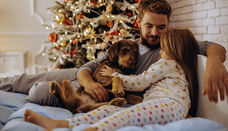 Vader met dochter en hond op schoot voor kerstboom