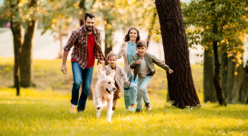 Familie løber med hund over en eng