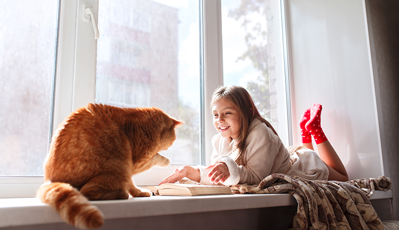 Kat zit bij kind in de vensterbank
